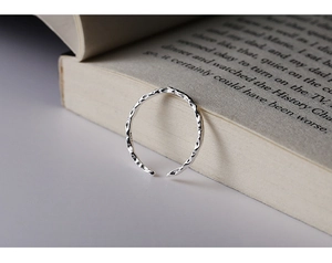 Macro di anello argento con texture martellata posato su una pagina di libro aperta