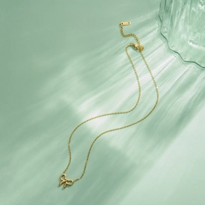 Close-up of gold bow necklace pendant showing K18 engraving and polished chain detail