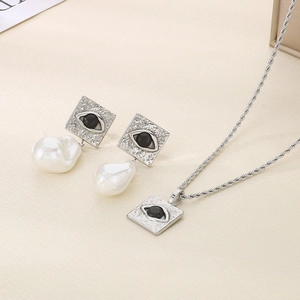 Macro detail of silver necklace and earrings set with baroque pearls and evil eye design