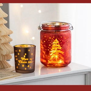 Detail of red and brown Christmas glass candle holders with warm LED lights and tree patterns