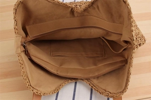 Detailed view of straw beach bag interior with zip pocket and brown fabric lining