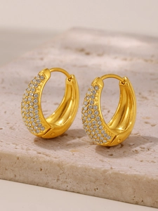 Detailed view of thick 18K gold-plated hoops with pave-set zircon on a stone pedestal