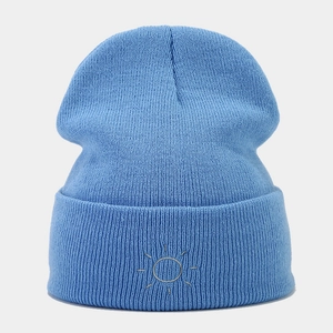 Close-up detail of light blue ribbed knit beanie featuring minimalist sun embroidery