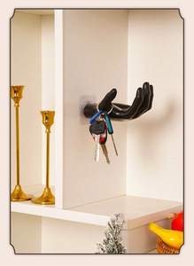 Detailed view of hand-shaped wall hook in black holding keys on a white surface