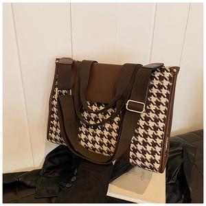 Close-up of houndstooth fabric texture and brown leather trim on a vintage tote bag
