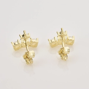 Macro view of gold stud earrings featuring triple white opal stones with claw setting