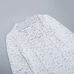 Gros plan détaillé sur la dentelle florale blanche et les coutures ajourées du haut à col carré