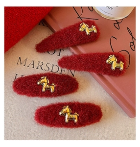 Dettaglio di quattro fermagli per capelli in velluto rosso con decori di cavallo dorati