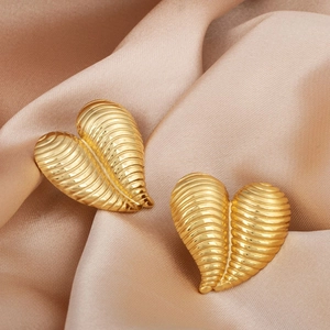 Textured gold heart earrings with 3D ribbed design displayed on elegant satin fabric