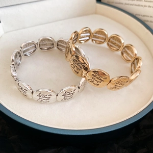 Close-up of gold and silver religious elastic bracelets with engraved scripture in a gift box