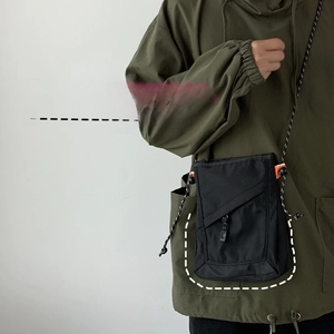 Detailed view of black nylon crossbody bag with adjustable strap worn on an olive hoodie