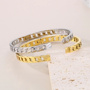 Detail of gold and silver stainless steel bangles with chain texture and side clasp closure