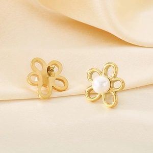 Macro detail of gold flower earrings with white pearl inlay on soft silk fabric