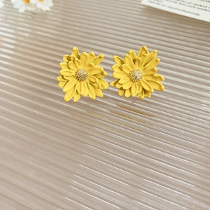 Macro close-up of yellow daisy flower earrings with fine petal details and silver needles