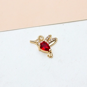 Detail of hummingbird jewelry pendant with gold plating, red gemstone and white zircons