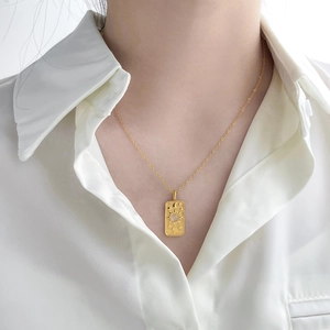 Detailed close-up of 18K gold plated tarot sun pendant necklace on a white shirt