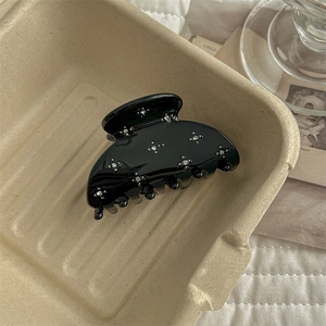 Detail of a black hair claw clip with rhinestones in a professional aesthetic setting