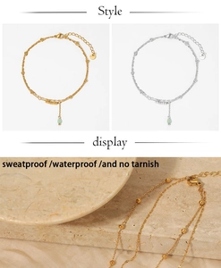 Detail of double-layered beaded chain anklet with a green teardrop charm, tarnish-free