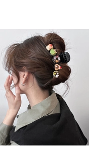 Macro detail of black hair claw clip with colorful resin donut and animal decorations