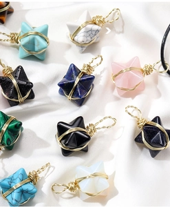 Flat lay of star-shaped crystal pendants with gold wire on white silk fabric background