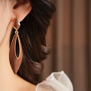 Detail view of brown vintage enamel teardrop earrings with gold plating on model
