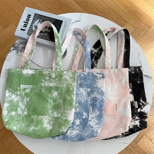 Dettaglio di borse tote colorate in tela tie-dye con tasche anteriori su un tavolo