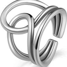 Primer plano de anillo abierto de metal plateado con capas entrelazadas pulidas