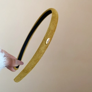 Détail du bandeau tricoté jaune gingembre avec bouton métallique Love gravé et texture