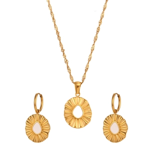 Golden sunburst necklace and earring set with white inlay on a clean white background