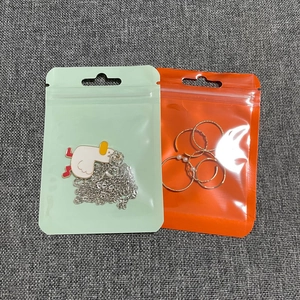 Detail of silver duck pendant necklace and gold pearl rings in transparent seal bags