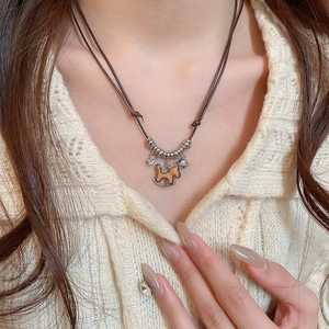 Close-up of wooden horse pendant and star charms on an adjustable brown cord necklace