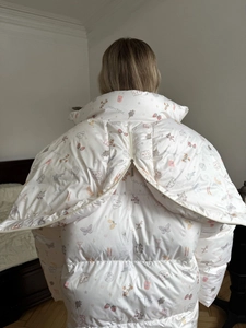 Rear view of white hooded jacket featuring colorful hand-drawn prints and back zipper detail
