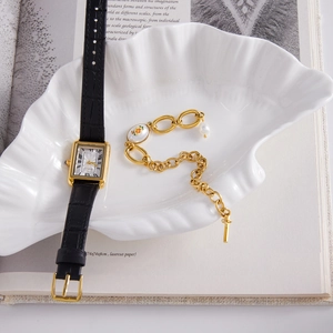 Coffret montre quartz vintage dorée et bracelet perles présenté dans un plateau coquille