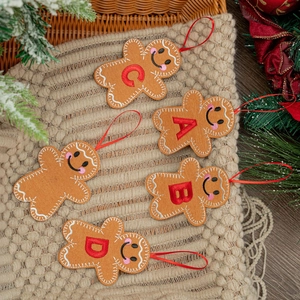 Gingerbread man plush ornaments with A-D alphabet embroidery on a cozy textured blanket