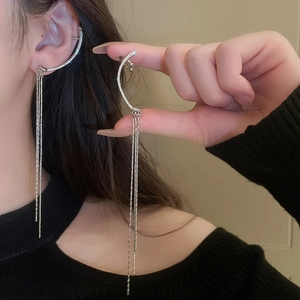 Detailed view of silver zircon tassel ear cuff with long dangling chains on ear