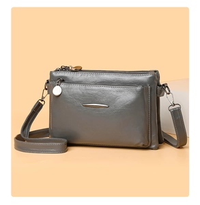 Detail view of grey multi-compartment crossbody bag with zipper and adjustable strap