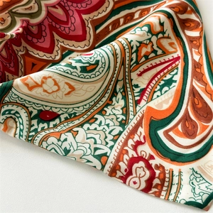Macro shot of paisley pattern fabric with vibrant red and green floral print details