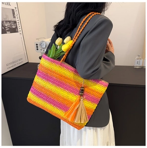 Close-up of rainbow striped straw tote bag with decorative wooden beads and tassel