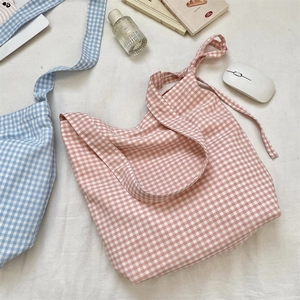 Detail of pink plaid canvas tote bag with decorative bow handles and cotton texture