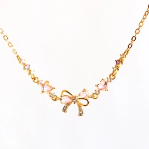 Detailed view of gold O-chain necklace featuring pink heart stones and a bow pendant
