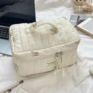 Close-up of quilted cream makeup bag with rabbit embroidery and decorative ribbon handle