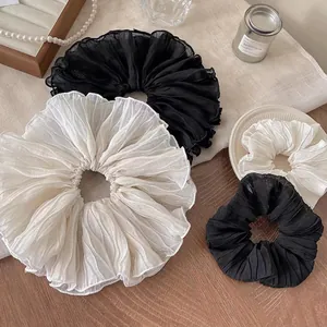 Oversized pleated chiffon scrunchies in black and white set on a wooden table