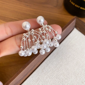 Elegant vintage tassel earrings with silver chains and white pearls in a handheld shot