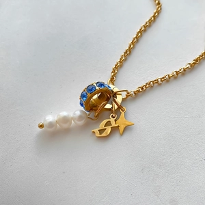 Macro view of 14K gold plated necklace with white pearls, blue crystals, and a star charm