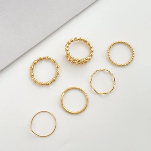 6-piece minimalist gold wave ring set with beaded textures and smooth bands on white background