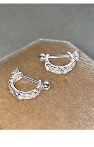 Macro detail of U-shaped silver zircon earrings with secure screw-back ball closures