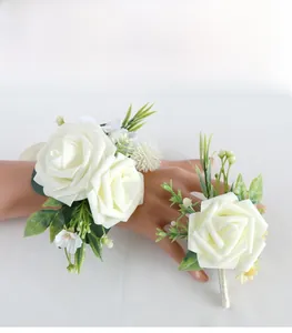 Detail of white artificial rose wrist corsage and boutonniere set for wedding ceremony