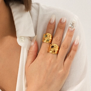 Gold hammered open rings with tiger eye stone worn by a model on white linen fabric