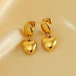 Macro view of 18K gold plated titanium heart drop earrings on textured satin fabric