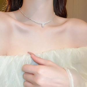 Detailed view of silver necklace with zircon pearl pendant worn on female collarbone